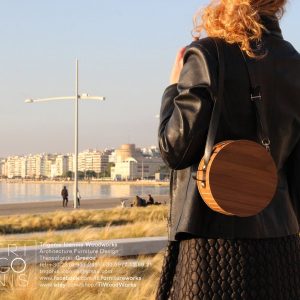 Small round wooden pouch bag made of veneered walnut and black leather handle